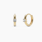 14k yellow gold diamond huggie hoop earrings featuring a sleek, polished design with a round brilliant-cut diamond set at the center. A modern and elegant everyday essential.