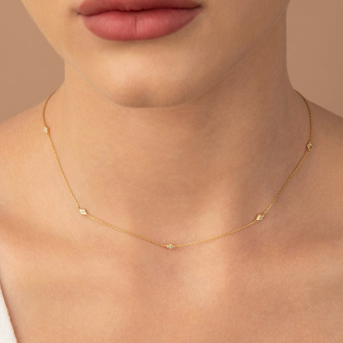 Model wearing a yellow gold multi-diamond necklace, styled close to the collarbone for an elegant everyday look.