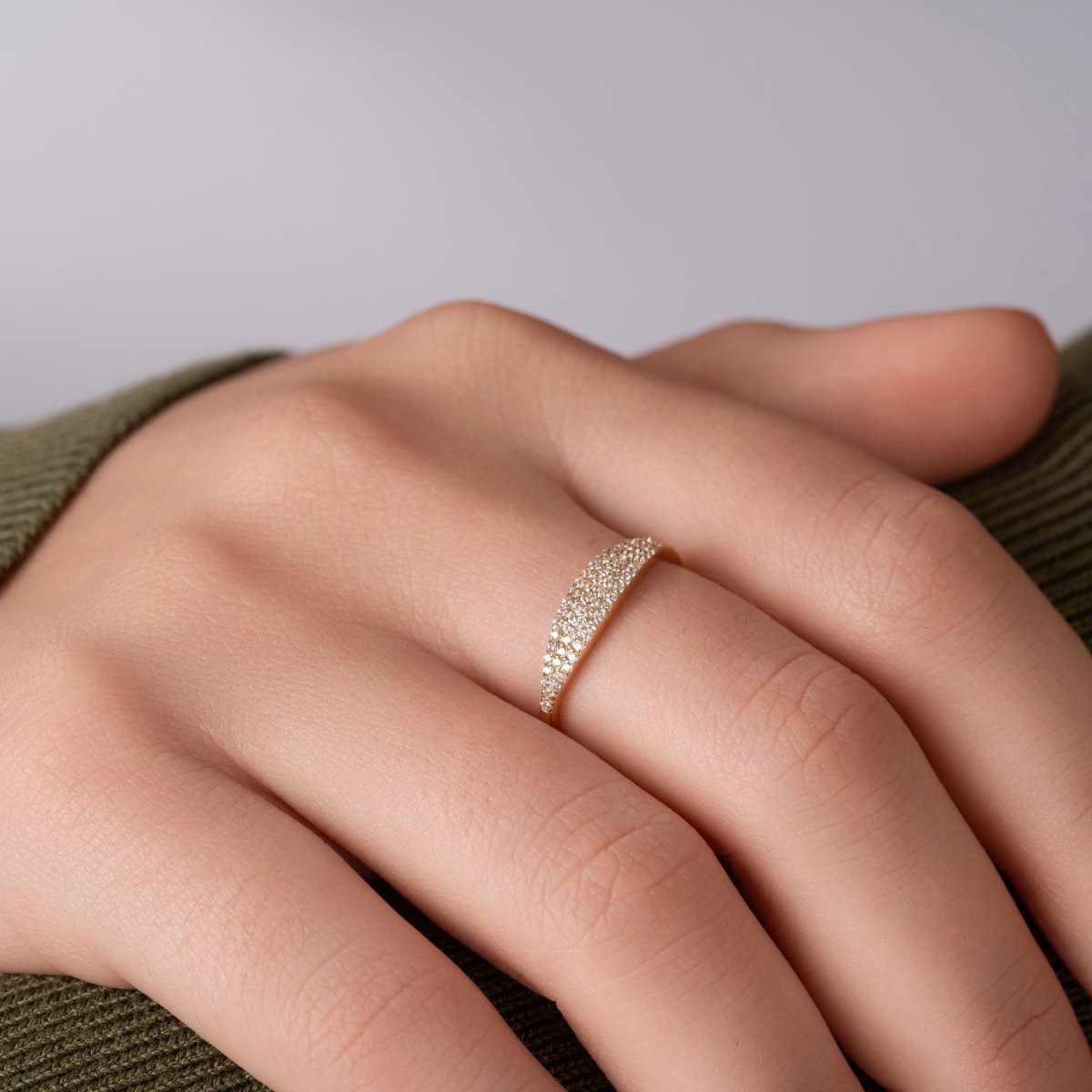 A woman styled with a 14k yellow gold pavé diamond band, showcasing its luxurious diamond detailing and curved silhouette in a natural setting.