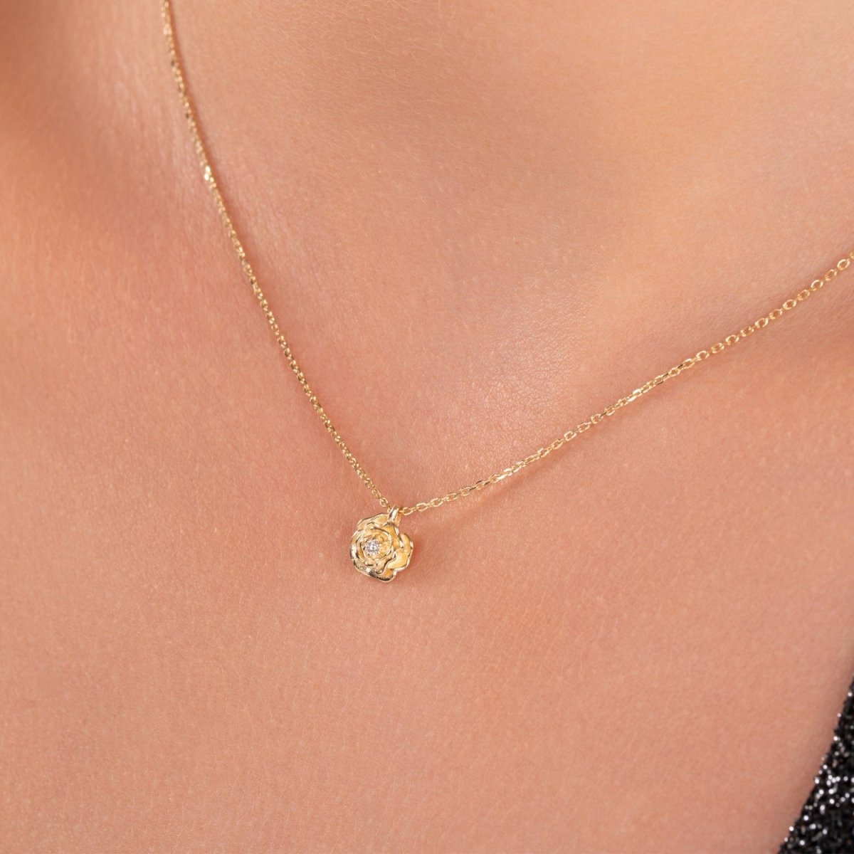 Detailed view of the diamond-studded rose pendant resting on the chest, worn on a delicate gold chain.