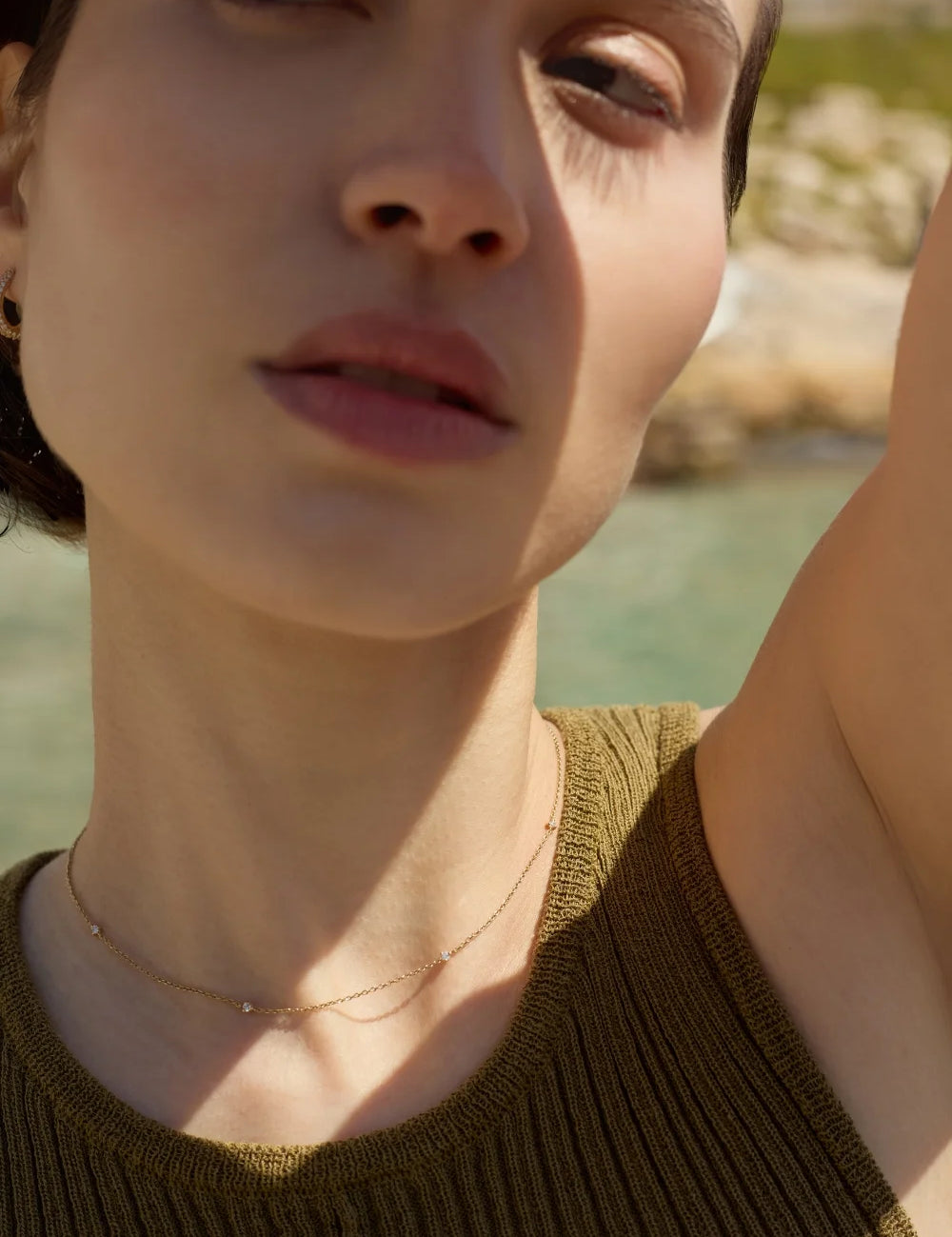 Close-up of a woman wearing a dainty 14k gold necklace with evenly spaced tiny diamonds, worn on her neck-ENEA