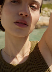 Close-up of a woman wearing a dainty 14k gold necklace with evenly spaced tiny diamonds, worn on her neck-ENEA
