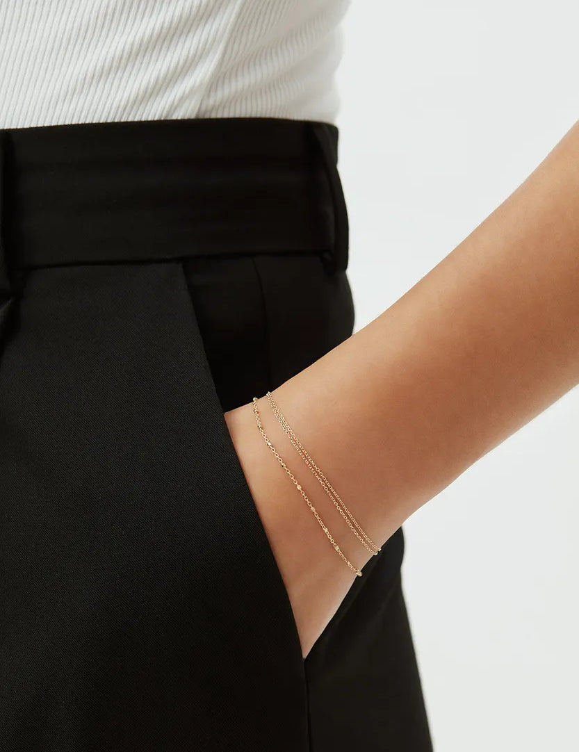 14k gold beaded chain bracelet styled on wrist, paired with tailored black trousers, minimalist everyday jewelry by ENEA