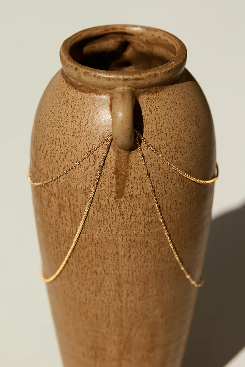 14k gold bracelet draped over ceramic vase, showing chain length and bead spacing, photographed in natural light