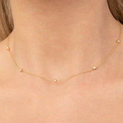 Model wearing the 14k yellow gold diamond station necklace styled elegantly on bare skin.