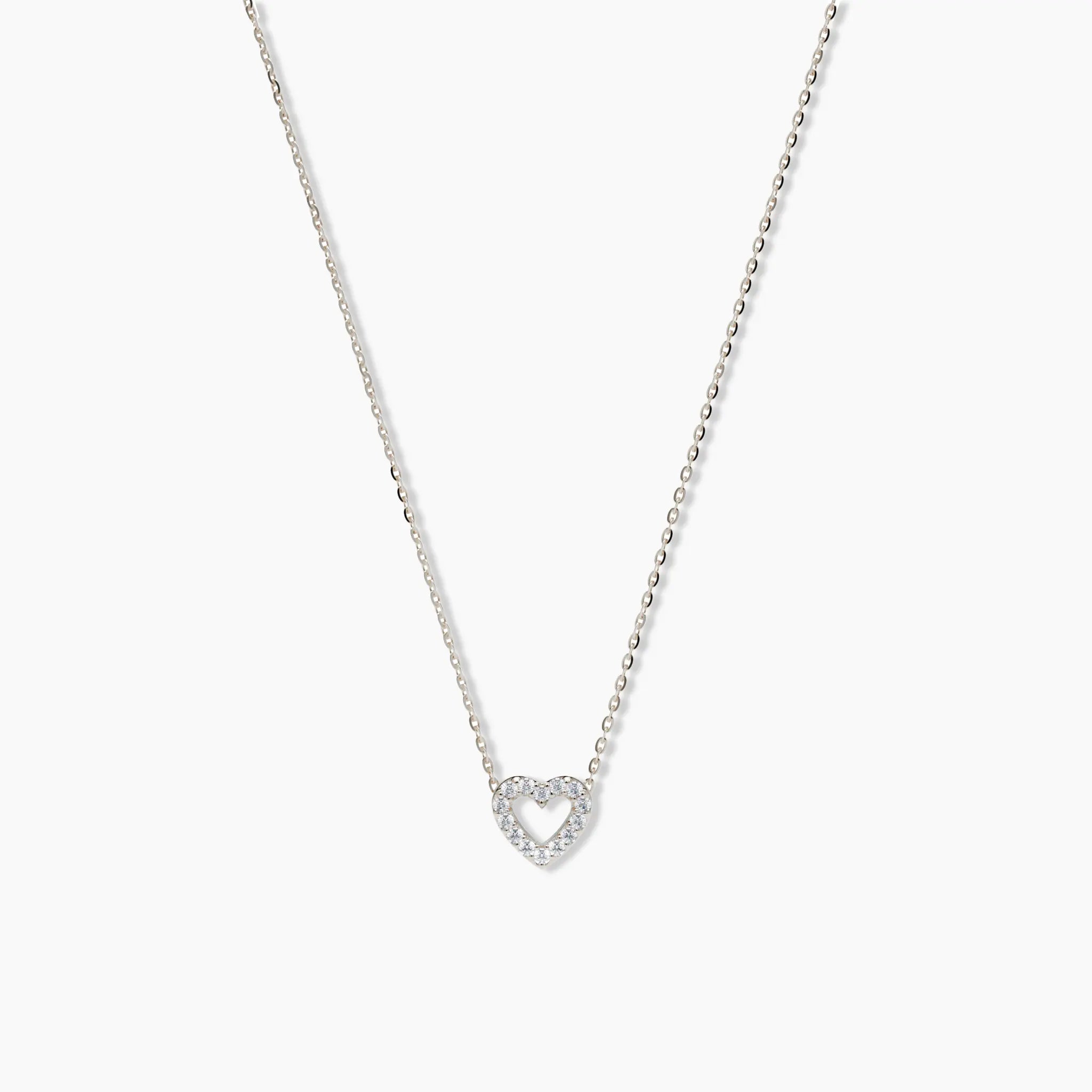 White gold pavé diamond open heart necklace photographed on a white background, showcasing its delicate chain and minimalist charm.