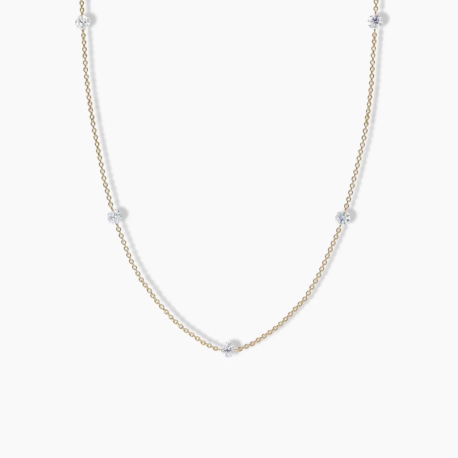 Minimalist yellow gold necklace with evenly spaced round diamonds set along a delicate cable chain, displayed on a white background.