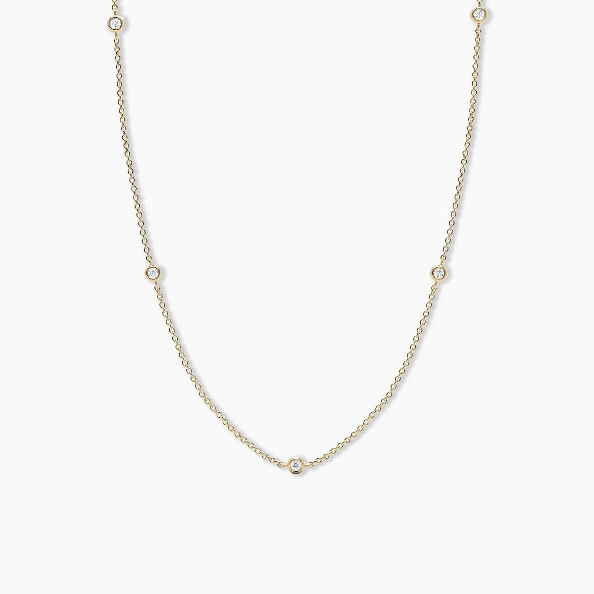 Gold necklace with small round diamond pendant on a white background