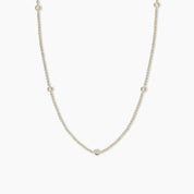 Gold necklace with small round diamond pendant on a white background