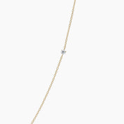 Product close-up of the necklace against a white background, focusing on the center diamond and fine 14k yellow gold chain.