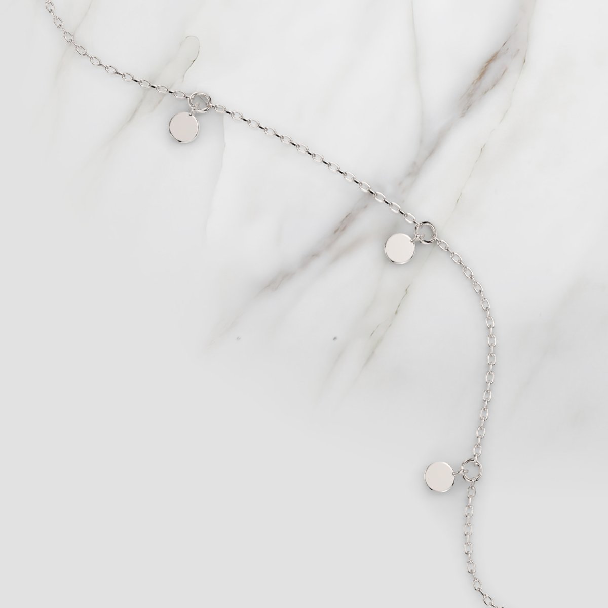 white gold disc necklace photographed on marble – modern design with polished coin-like drops.