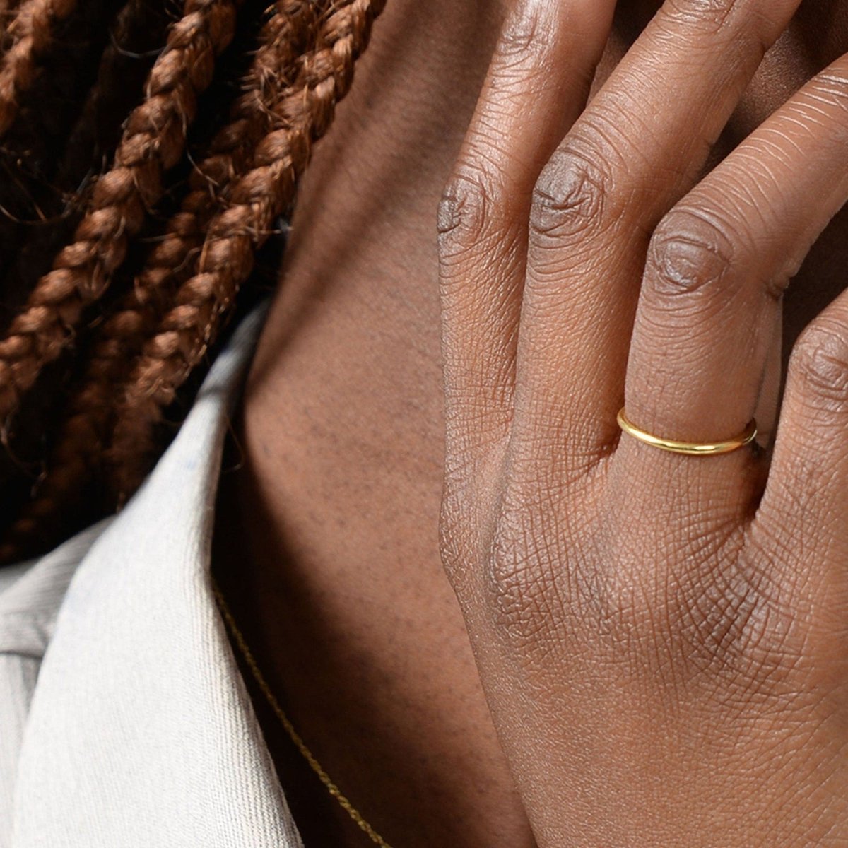 A close-up of a woman’s hand wearing a 14k yellow gold thin band, highlighting its sleek and minimalist design.