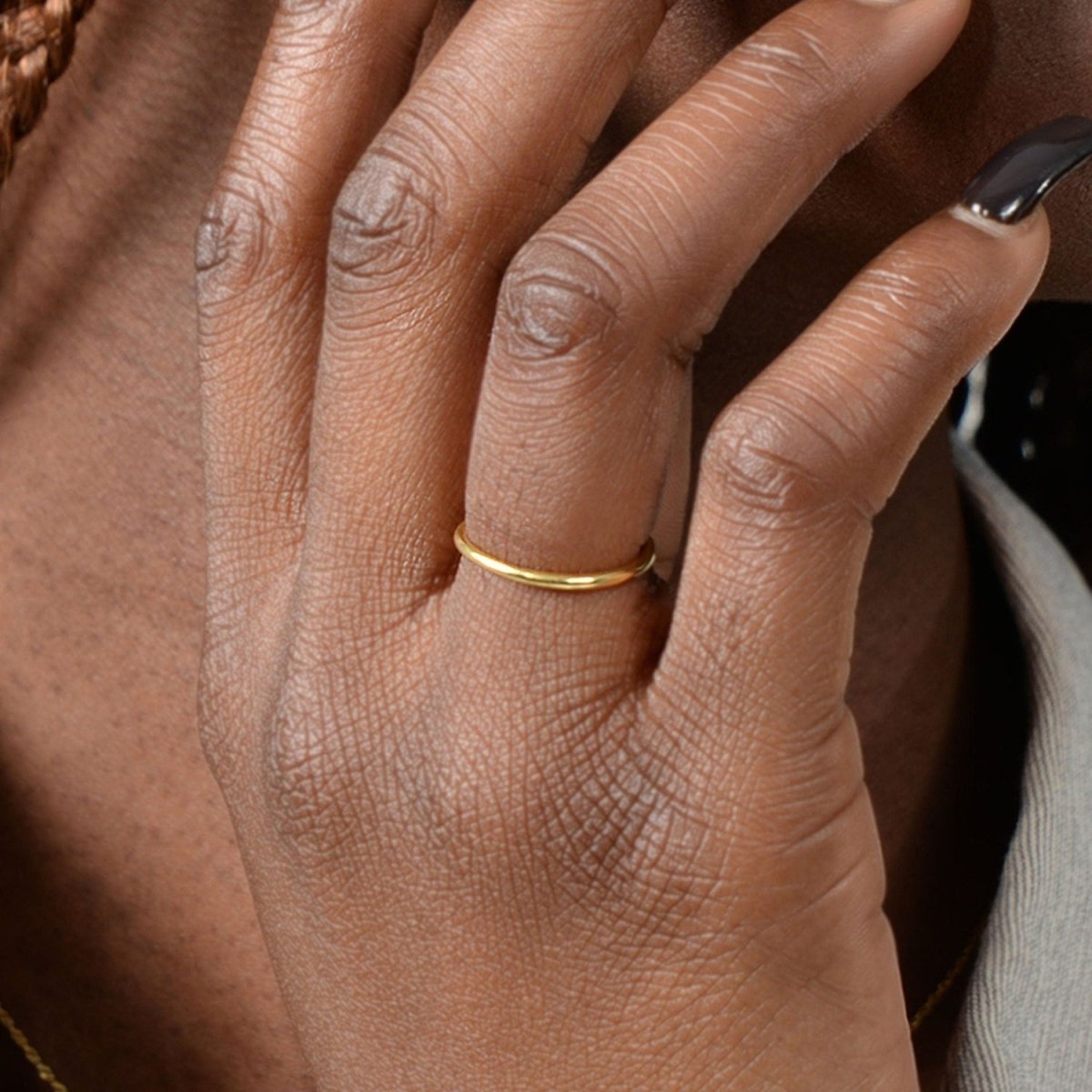 A woman’s hand adorned with a 14k yellow gold thin band, styled effortlessly for a minimal and timeless look.