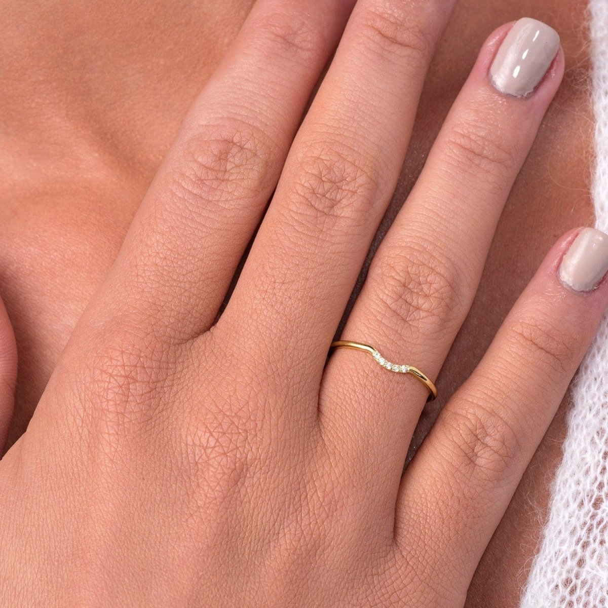 model wearing the yellow gold curved diamond ring on her finger, demonstrating its dainty fit and minimalist elegance