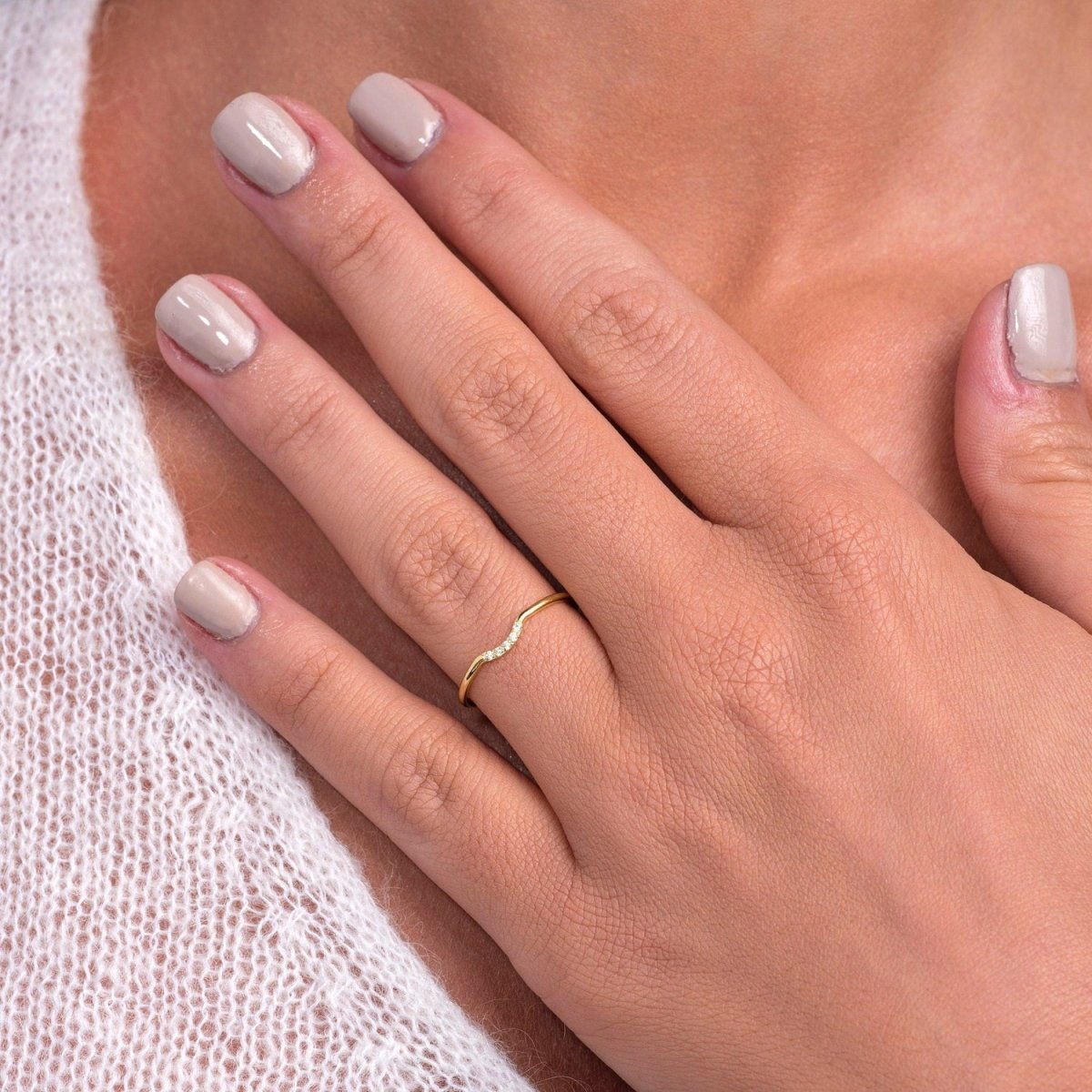 close-up of model's hand wearing the curved diamond ring in yellow gold, highlighting the delicate curve and precise diamond placement