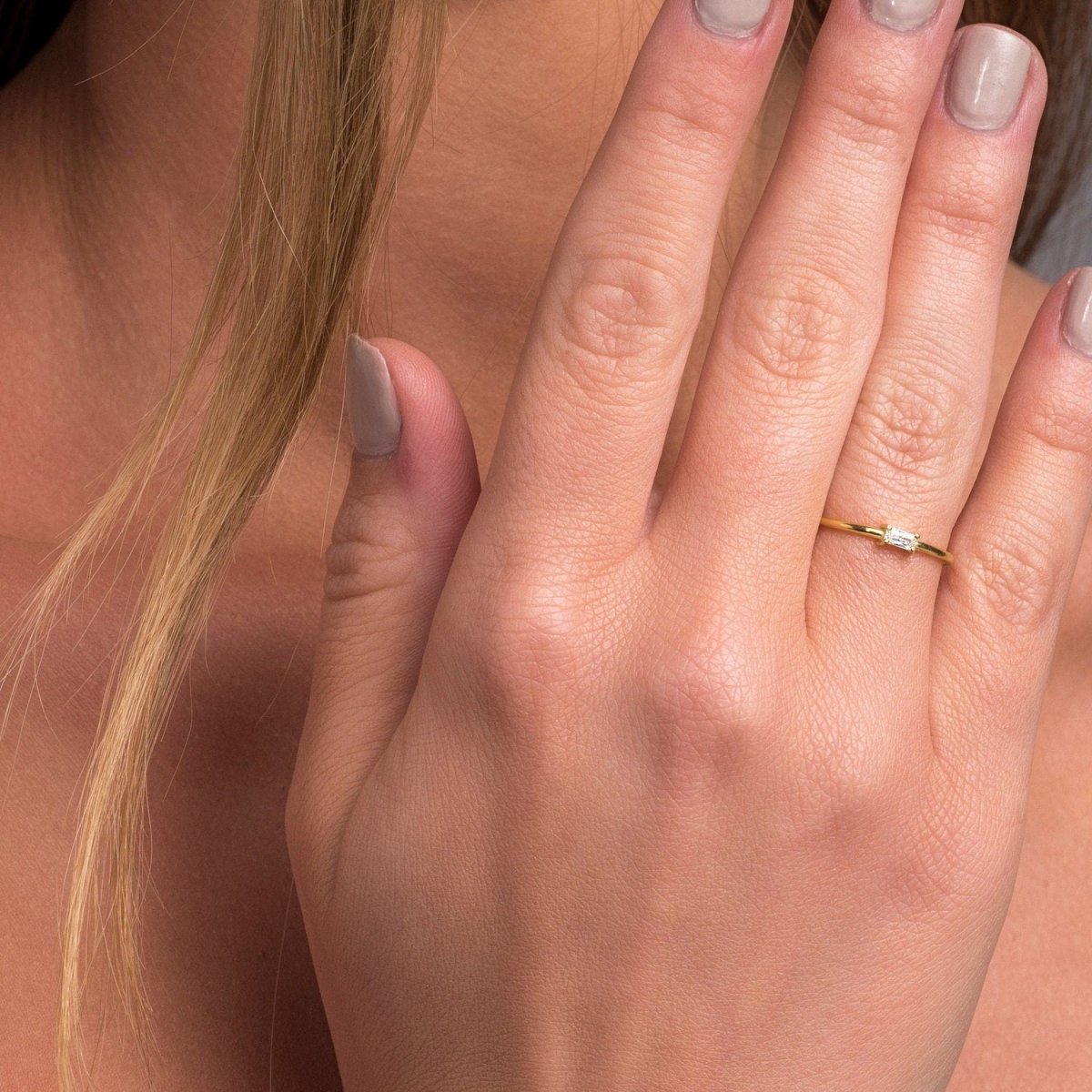 A model wearing a yellow gold baguette diamond ring, highlighting its dainty, refined design.