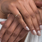 close-up of a model’s hands stacked with multiple rings, featuring the open cuff diamond ring in white gold as a centerpiece