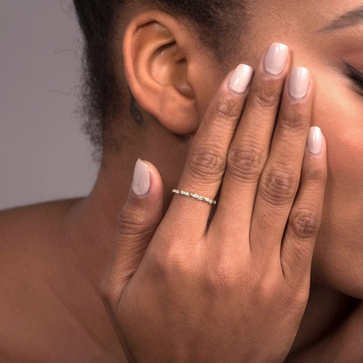 A woman’s hand adorned with a 14k white gold twisted diamond eternity band, emphasizing the fine twisted gold details and the shimmering row of diamonds.