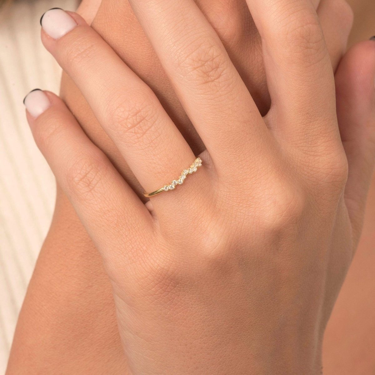 A close-up of a woman’s hand adorned with a 14k yellow gold cluster diamond band, showcasing its elegant clustered diamond design and sleek gold band.