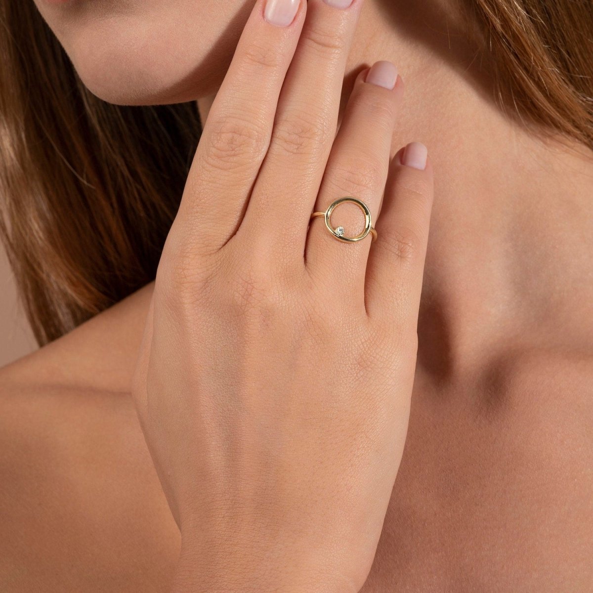 A woman wearing a 14k yellow gold open circle diamond ring, delicately styled on her hand for a minimalist and contemporary look.