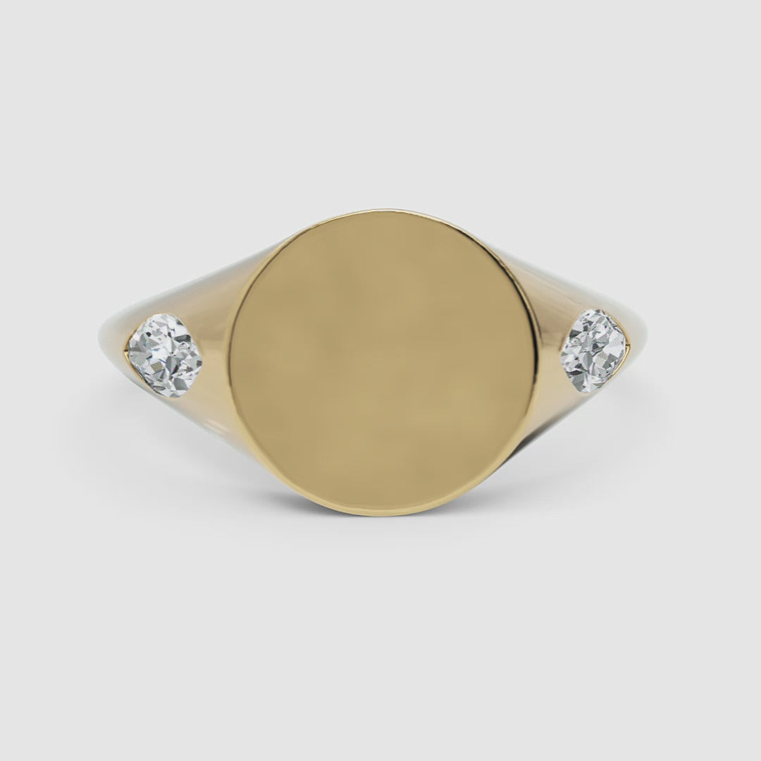 A 360-degree video of a 14k yellow gold marquise diamond signet ring, smoothly rotating to reveal its polished gold surface and two bezel-set marquise diamonds.