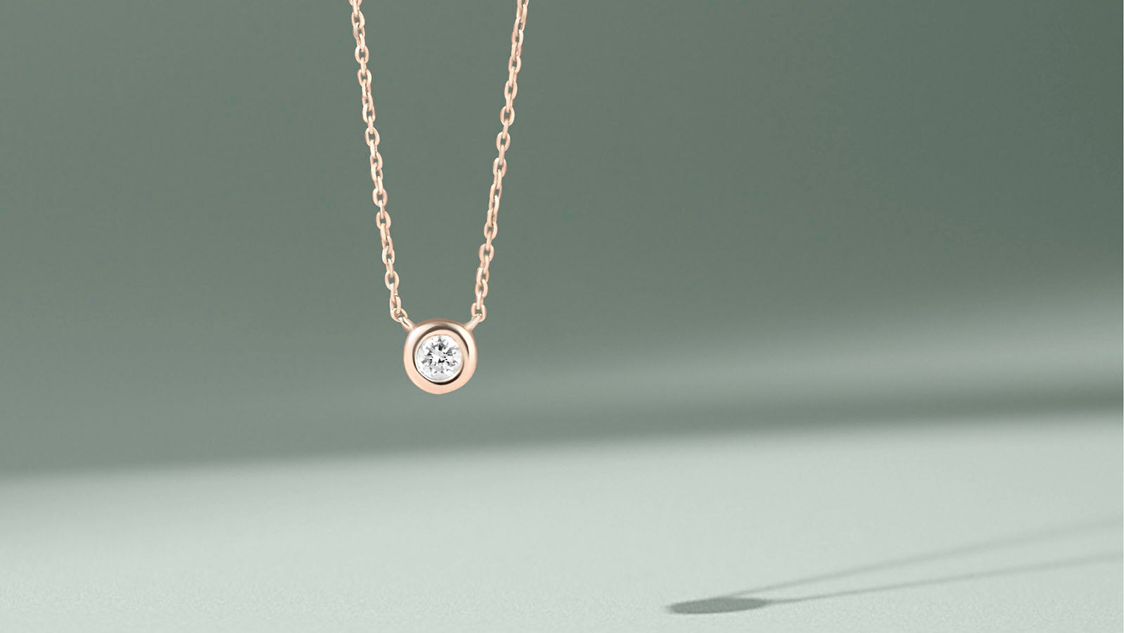 14k gold bezel set diamond necklace with delicate chain on soft neutral background