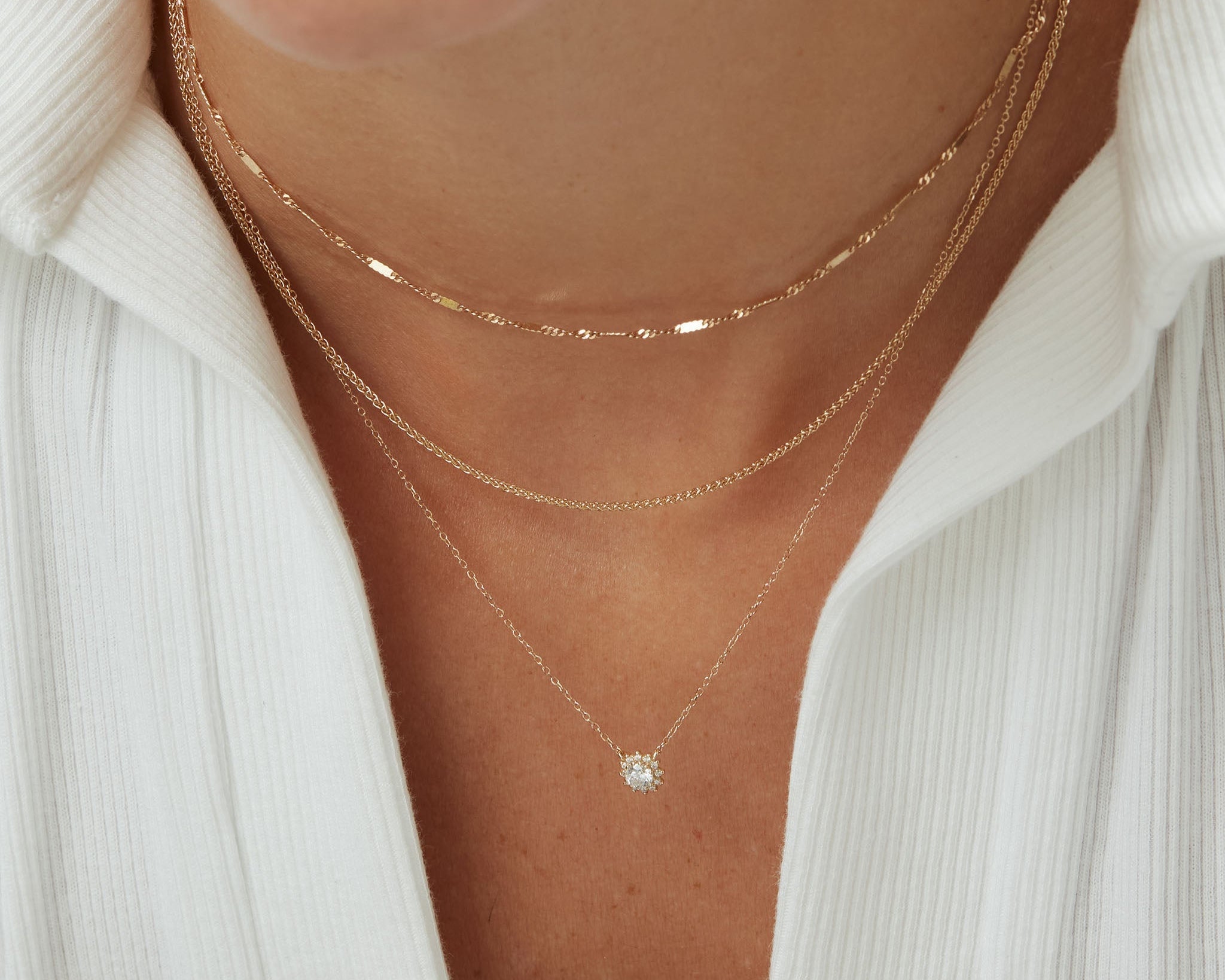 Layered solid 14k gold necklaces in varying lengths on neutral background by ENEA Studio