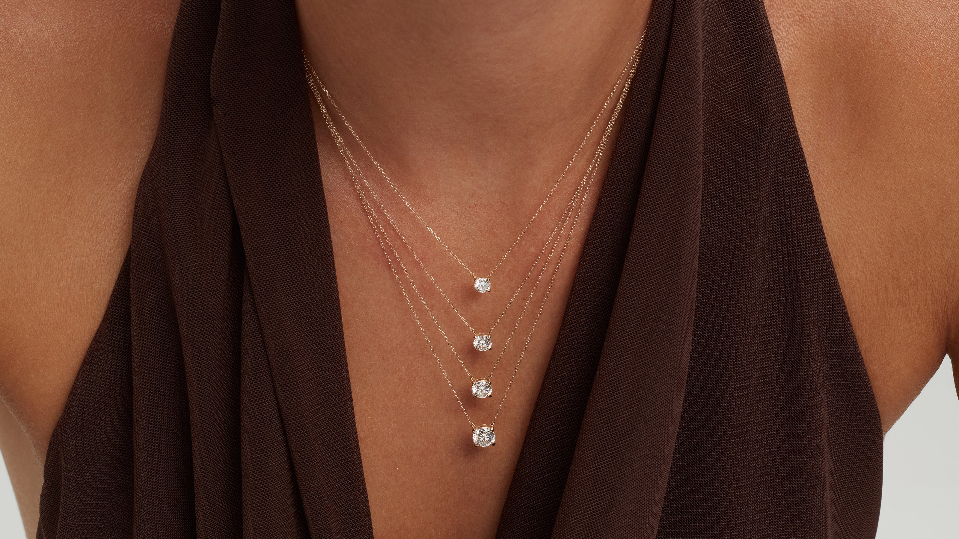 Lab grown diamond solitaire necklaces in 14k gold resting at a woman's collarbone
