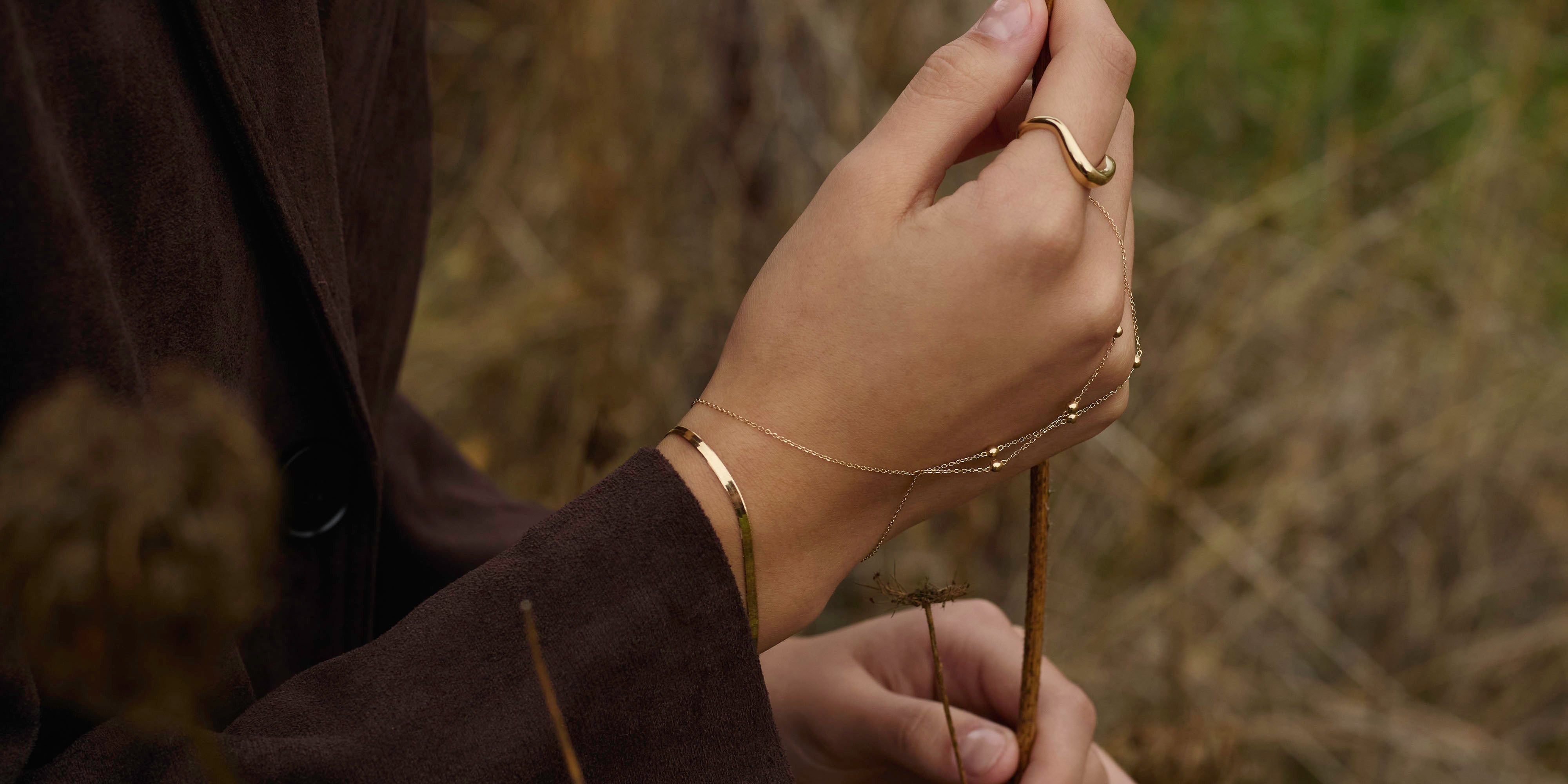 Stacked solid 14k gold bracelets layered on woman's wrist by ENEA Studio