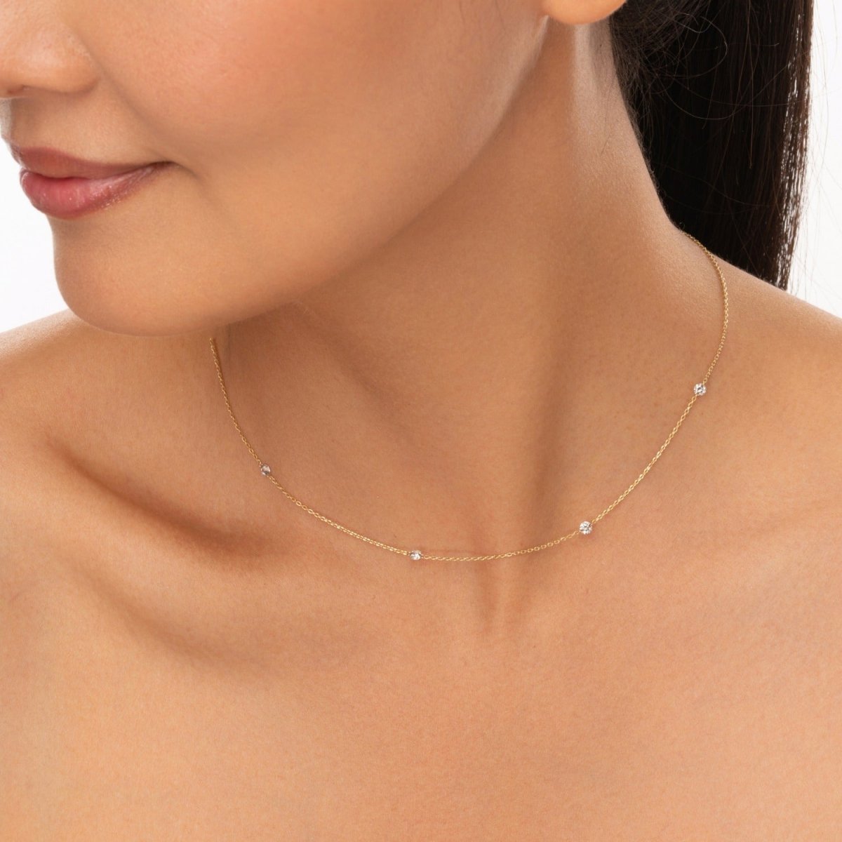 Necklace styled with elegance as the model looks down slightly, emphasizing the fine gold chain and sparkling stones.


