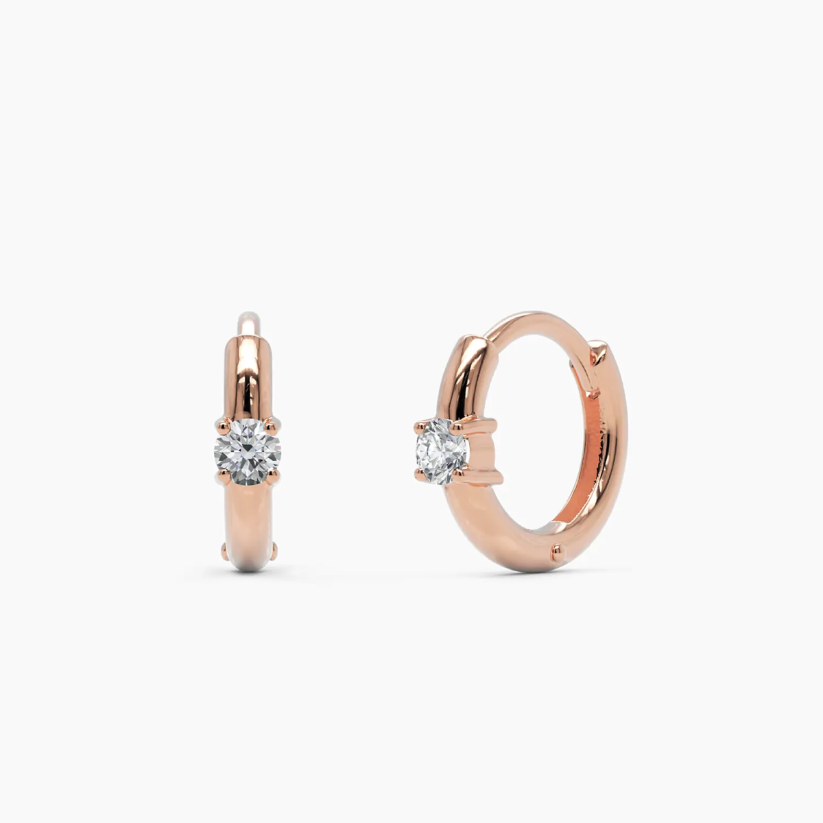 14k rose gold diamond huggie hoop earrings featuring a delicate hoop design with a single round brilliant-cut diamond. A warm-toned and contemporary jewelry staple.