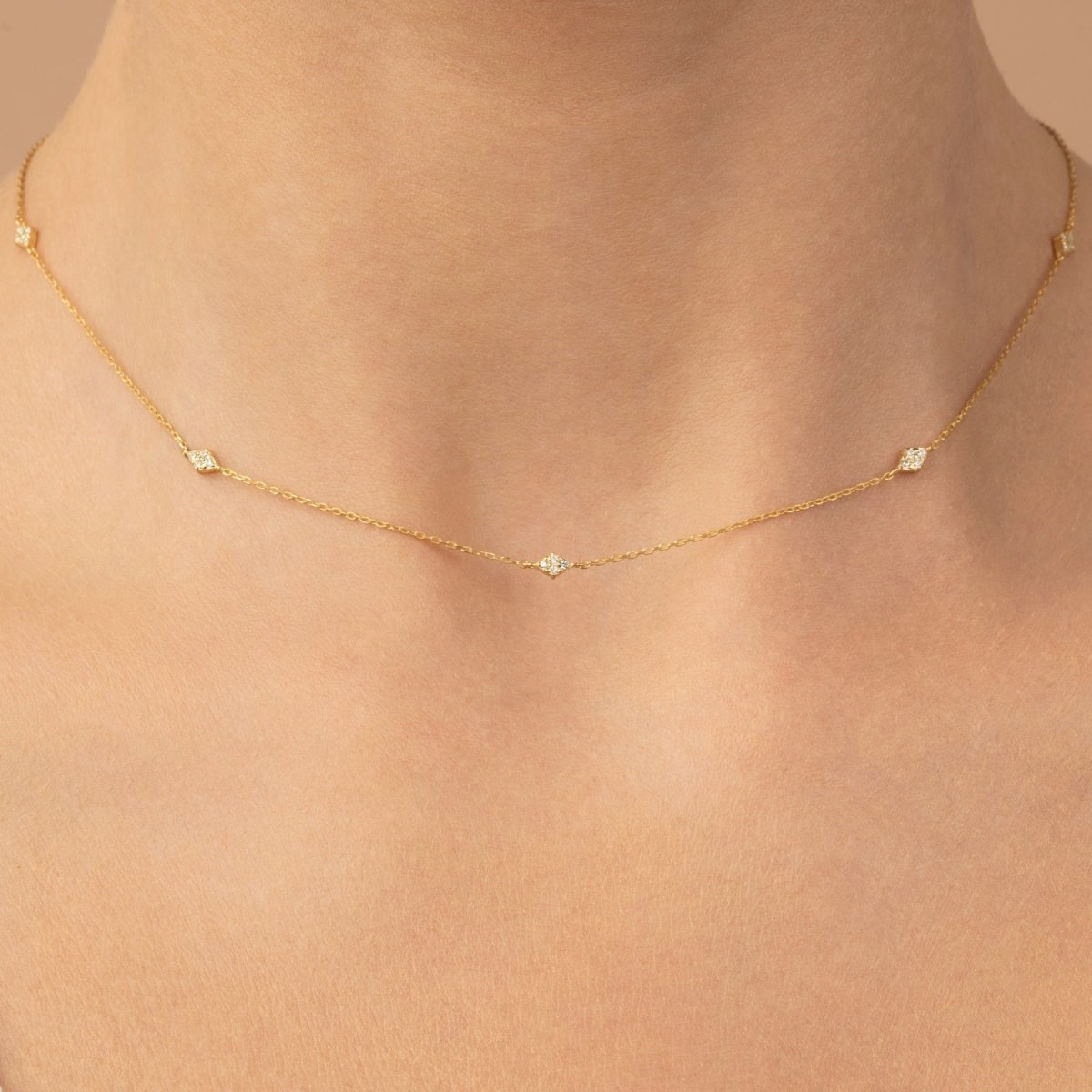 Model’s neck adorned with a dainty yellow gold necklace set with evenly spaced white diamonds.