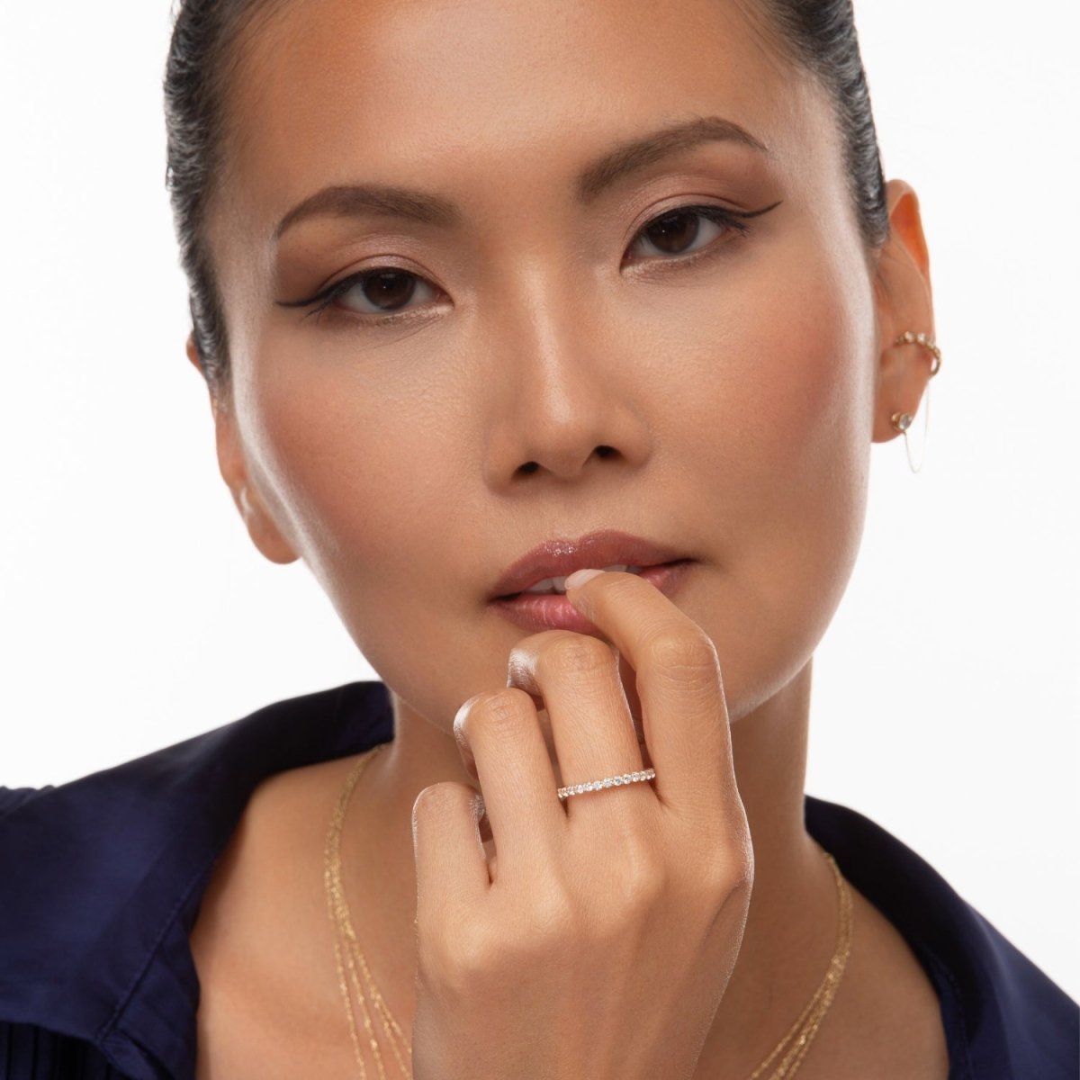 model gently touching her lips while wearing the diamond eternity band, emphasizing its refined and delicate design

