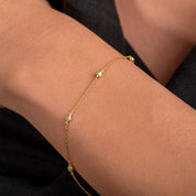 Model wears a 14k gold station bracelet with bezel-set diamonds, catching light naturally across the wrist.

