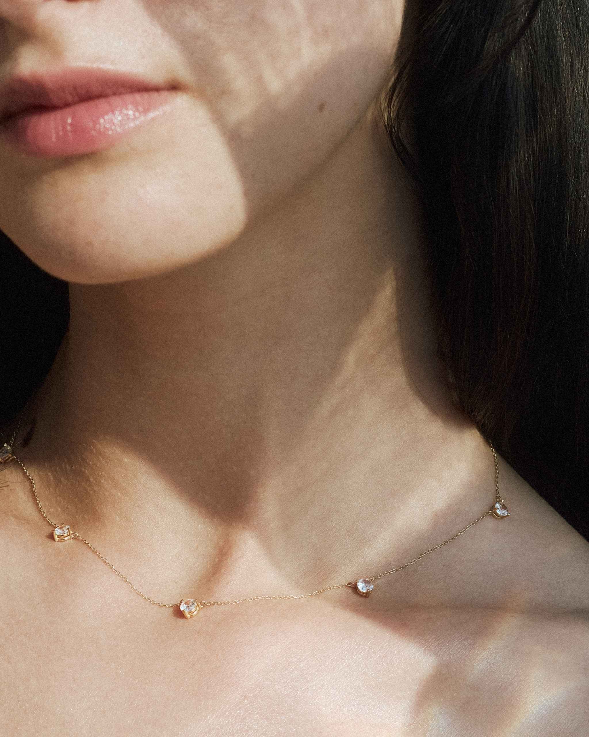 close up of the 14k yellow gold alinéa gold diamond station necklace ii worn on model 