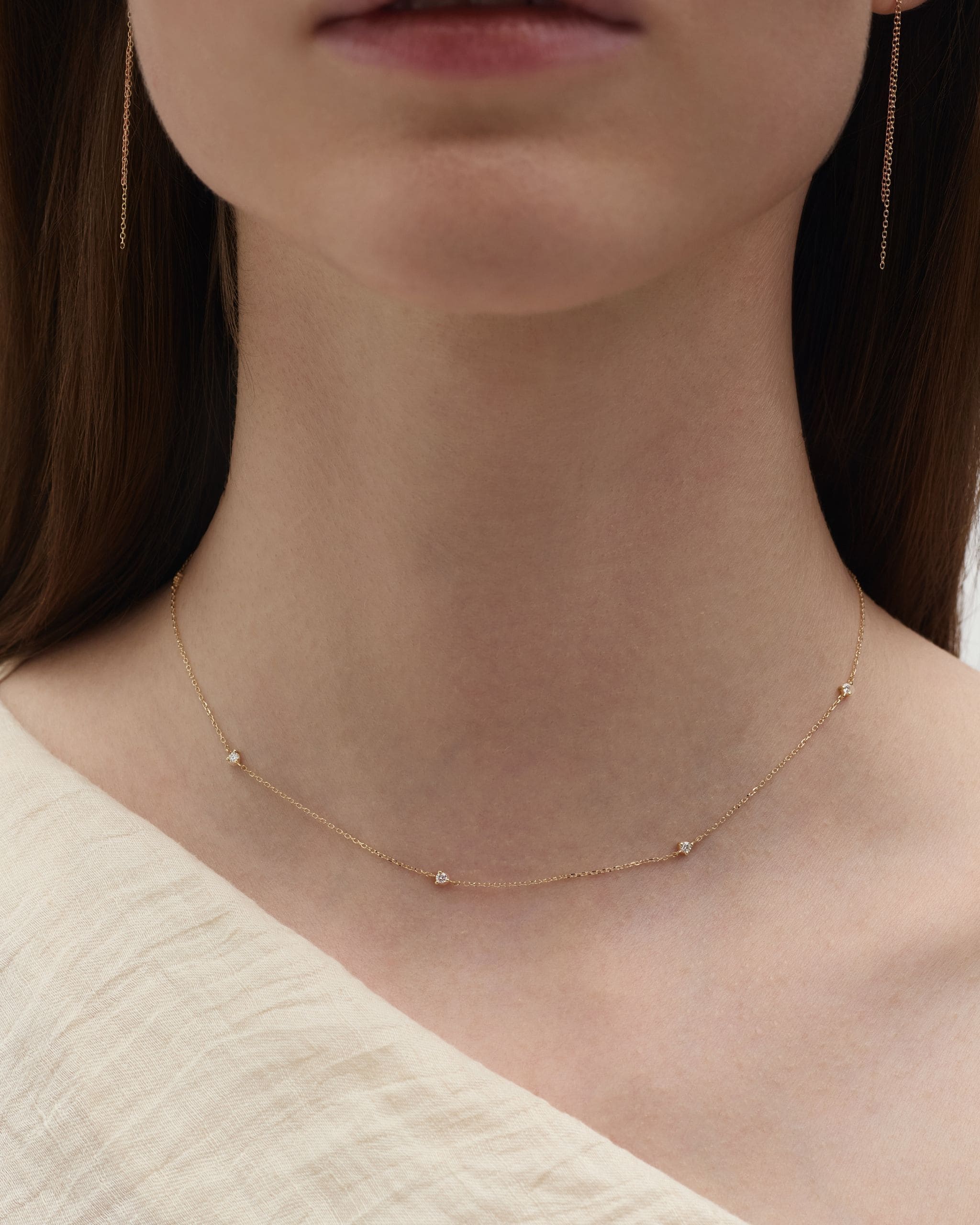 Close up of solid gold tiny diamond necklace on model neck showing delicate chain with small prong set diamonds. Enea Studio