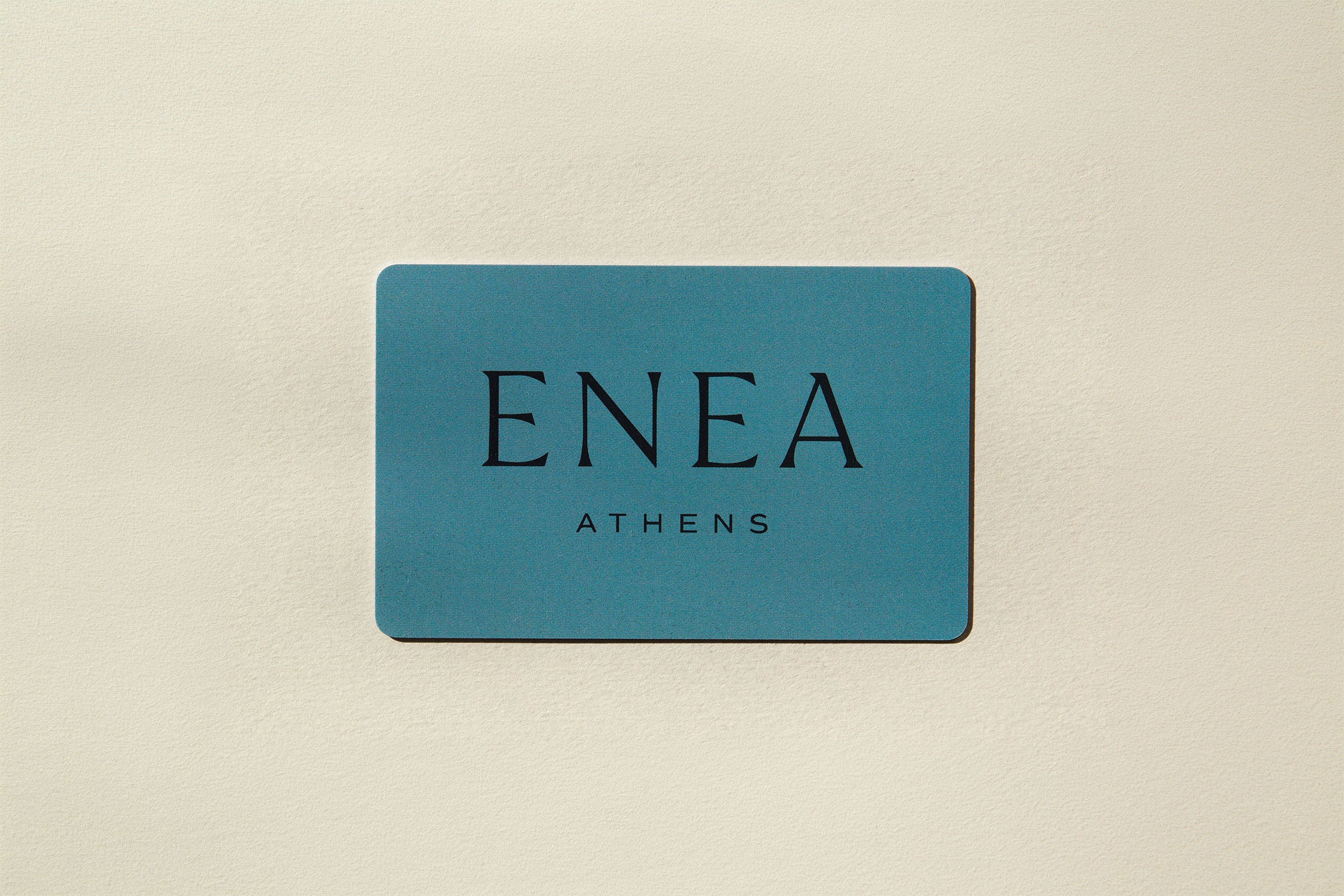 Green card with 'ENEA Athens' text written with black letters and placed on a beige surface
