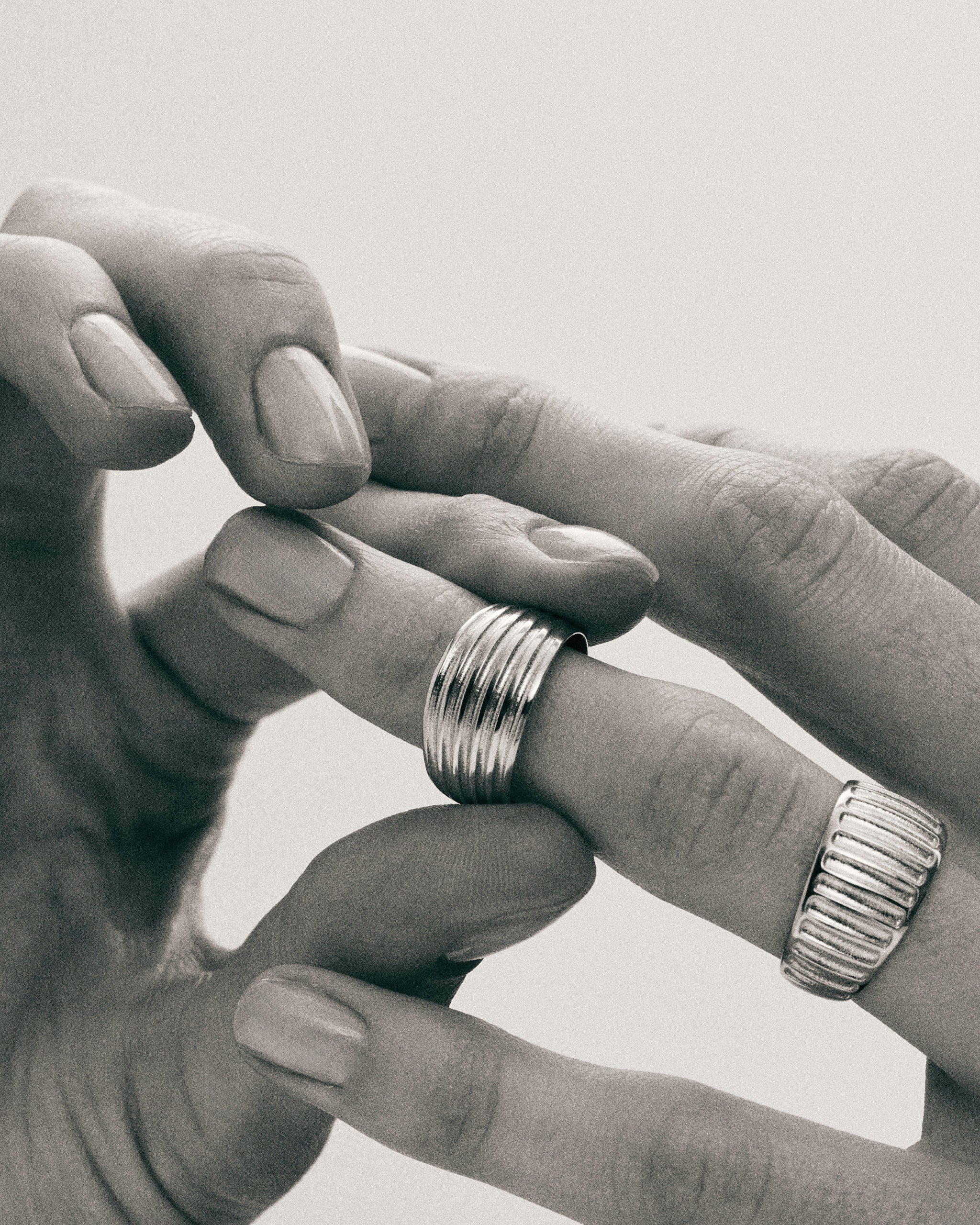 Black and white photo of hands wearing the Kion Ribbed Dome Rings by Enea Studio