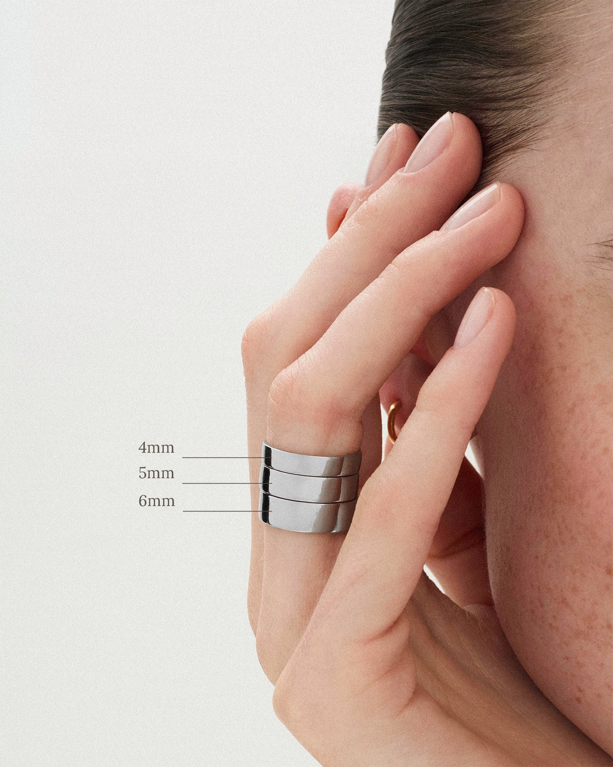 The Cigar Band Ring in 4mm, 5mm and 6mm widths worn stacked on a woman's finger against a neutral background 