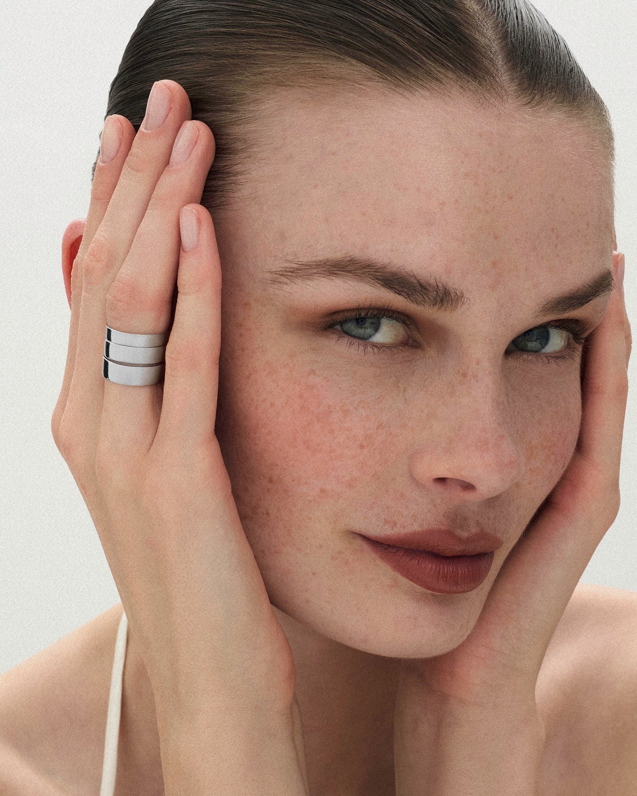 Woman with freckles wearing 3 different widths of the Cigar Band Ring on her finger in white gold by ENEA