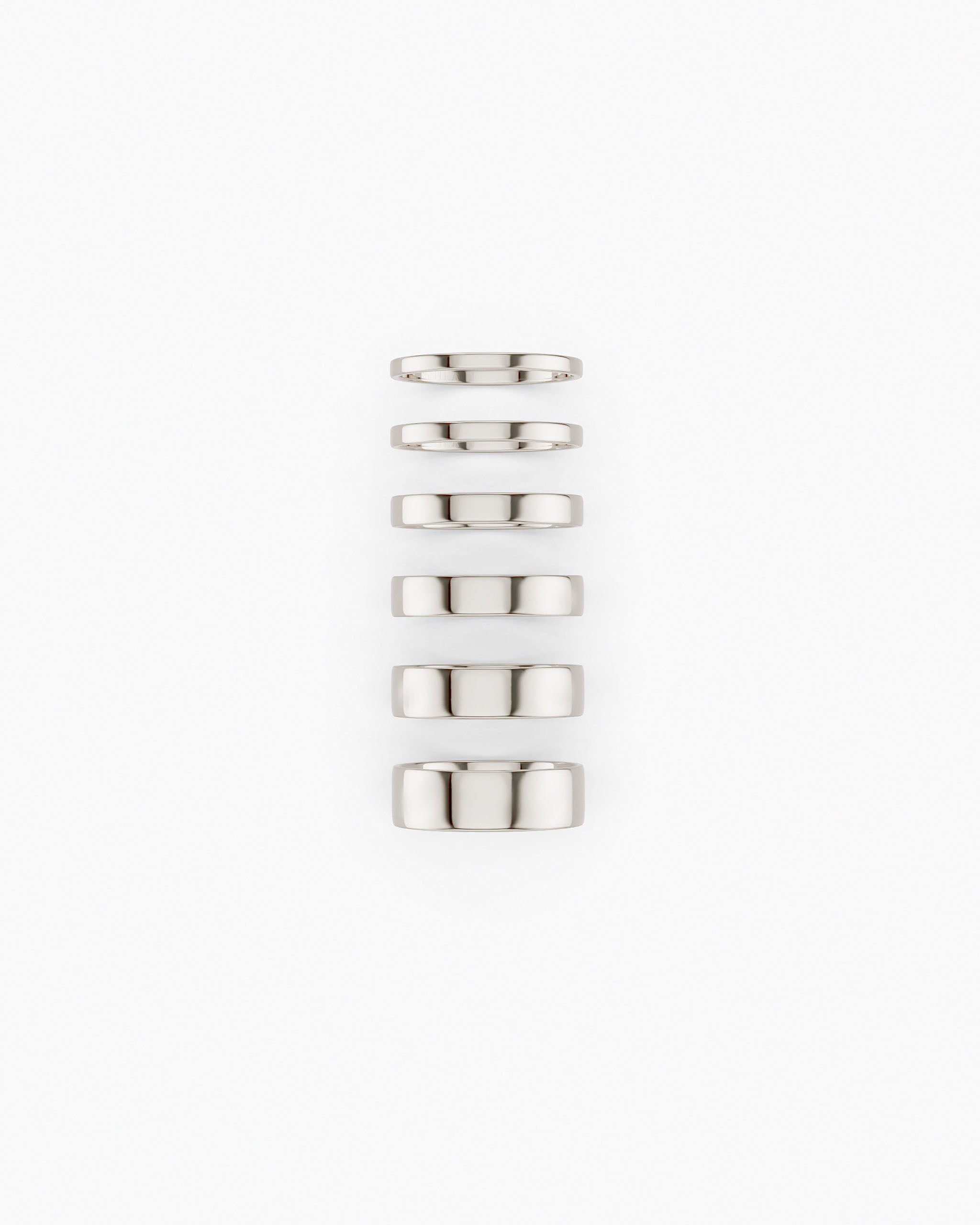 Six Cigar Band Rings made in white gold and in different widths stacked vertically on a white background