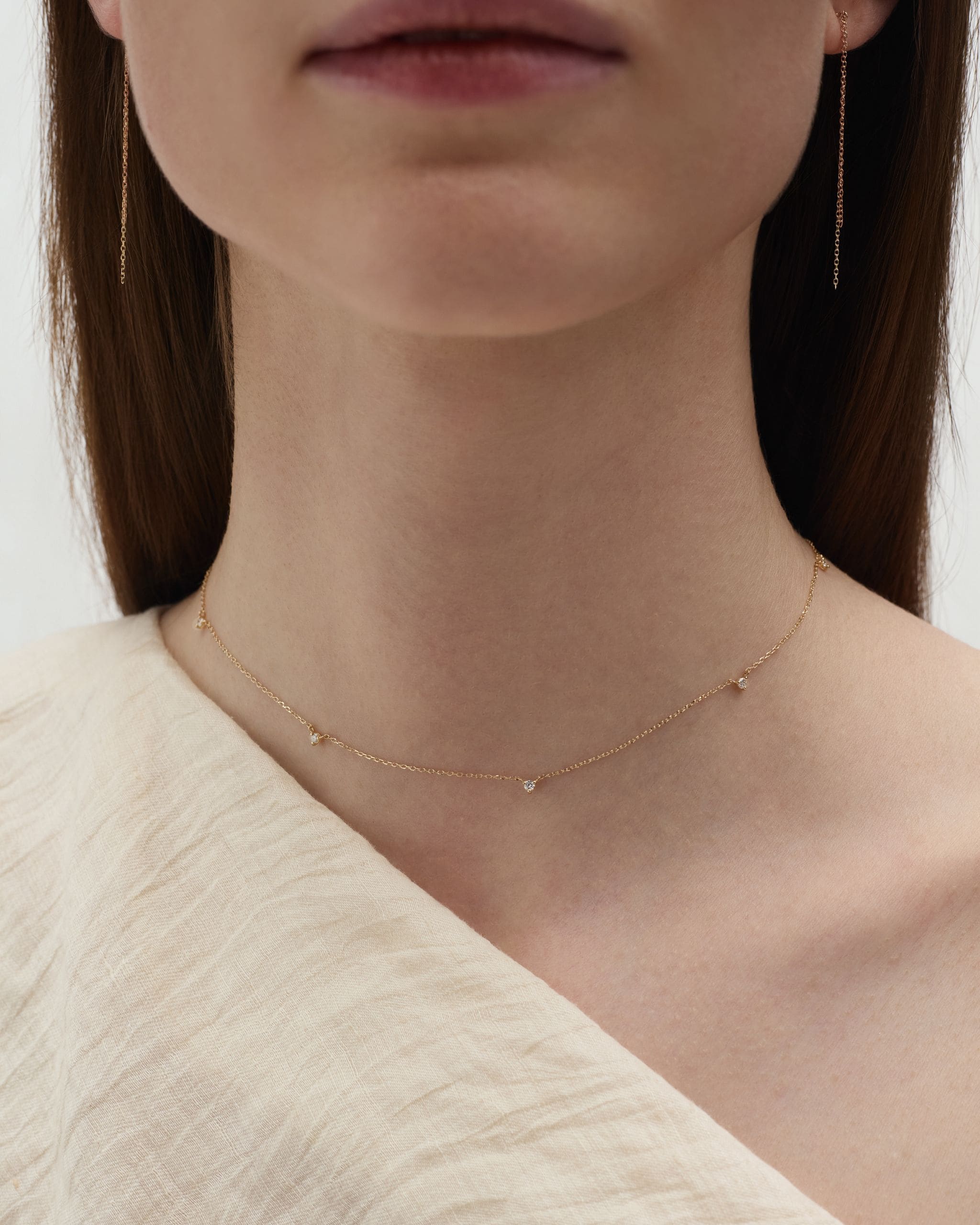 Model wearing solid gold diamond by the yard necklace showing full necklace with five station diamonds
