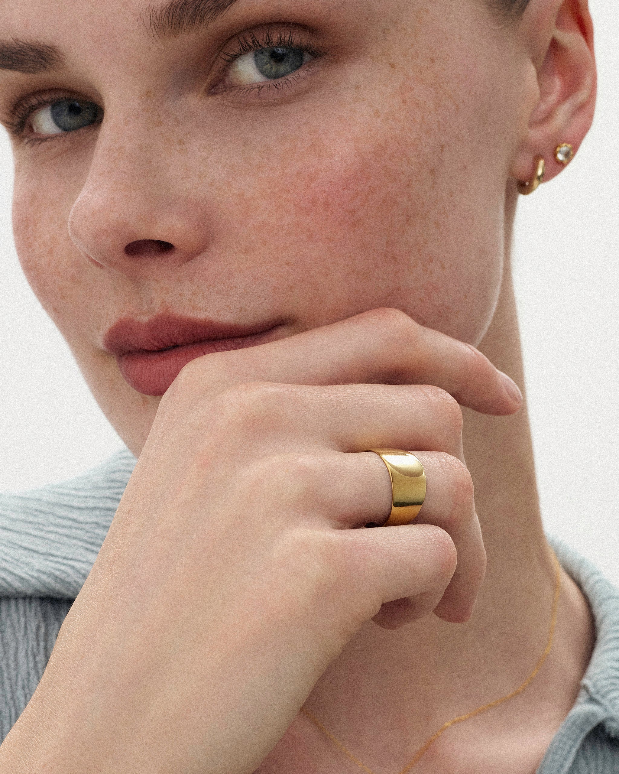 Woman holding her hand in front of her chin styled with the Kion Classic Dome Ring in solid yellow gold by ENEA