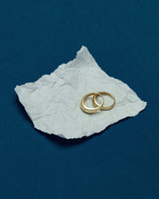 two solid gold dome rings placed on a crumpled piece of paper on a blue surface