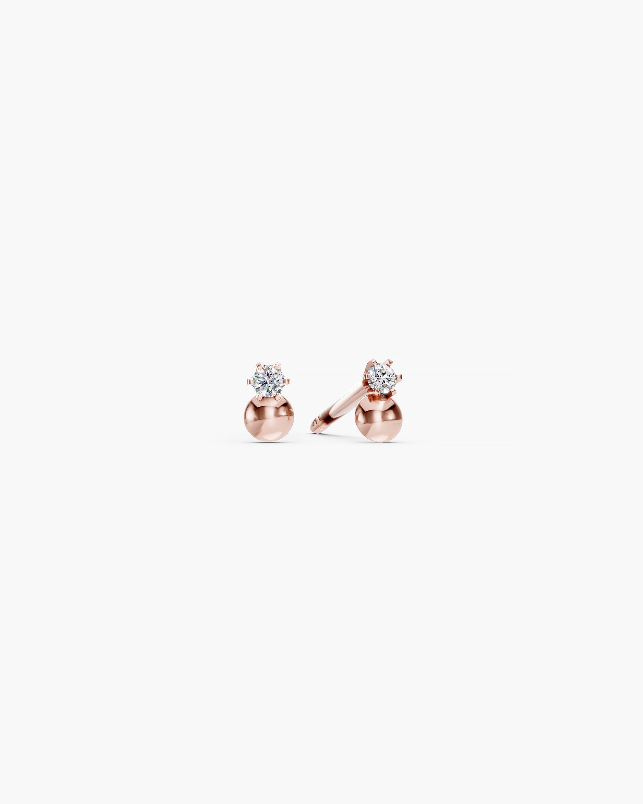 Dyo Diamond Bead Studs in 14k rose gold, front view, a lab grown diamond in six prongs above a polished rose gold bead, on an off-white surface. ENEA Studio