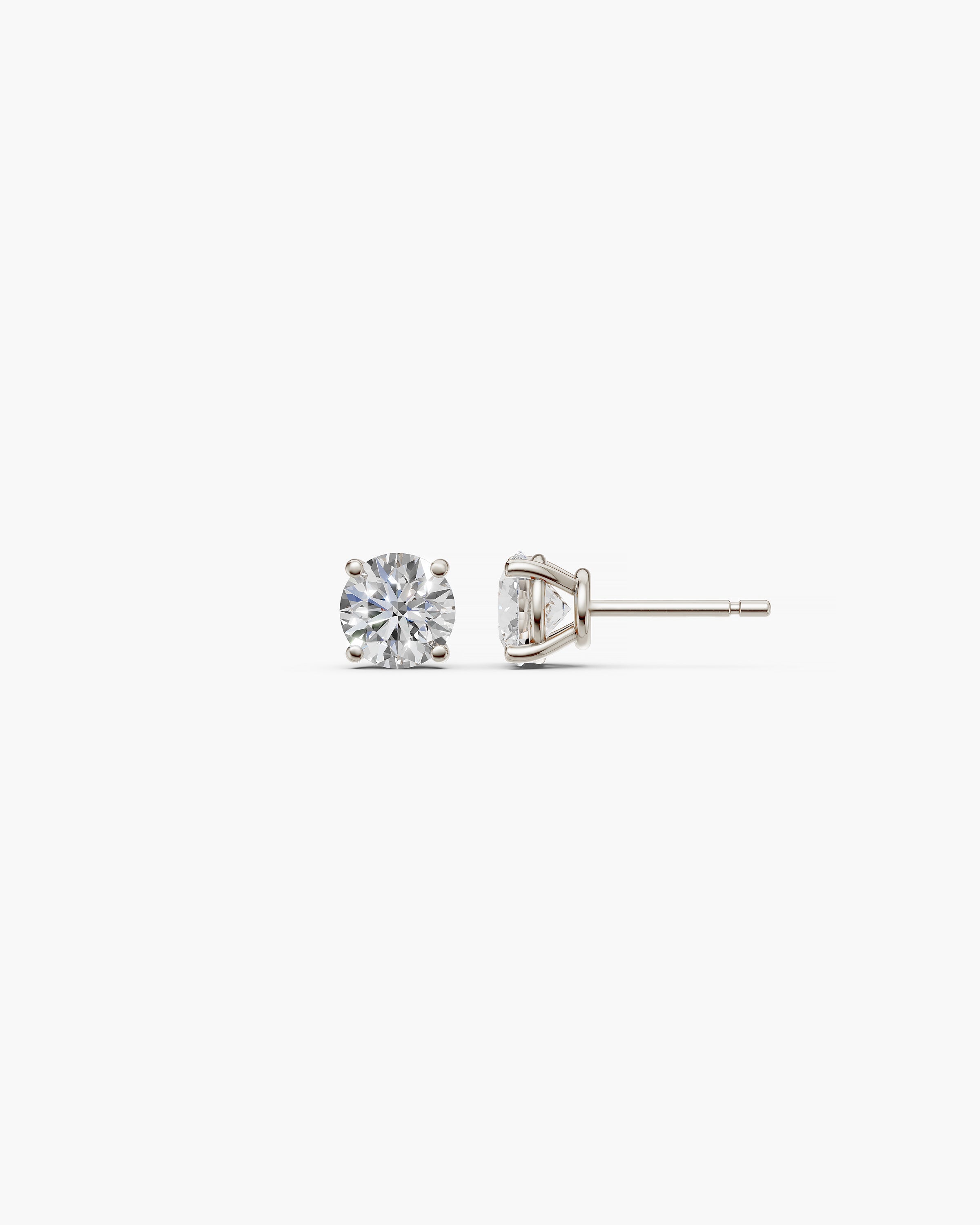 Eclat Grand Diamond Stud Earrings in 14k white gold on an off-white surface, side view