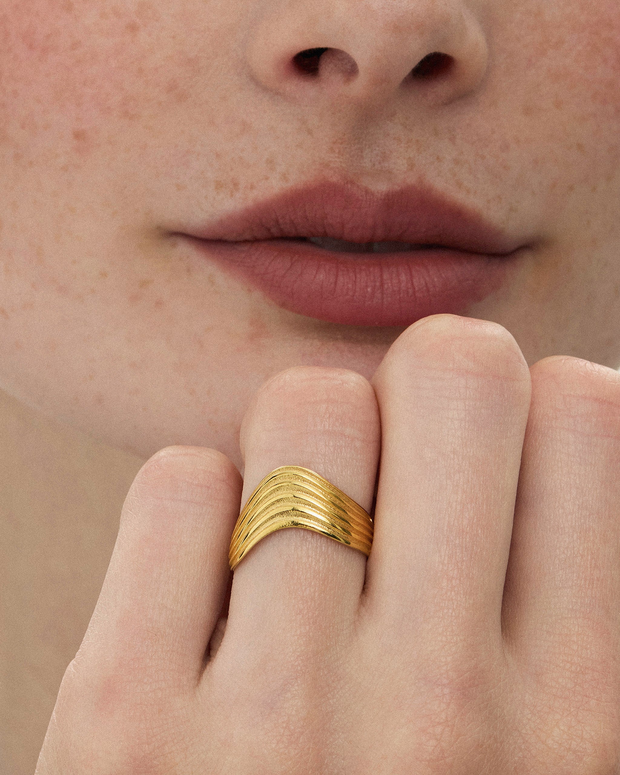Close-up of a woman wearing the Kion III Ribbed Wave Ring in solid yellow gold by ENEA