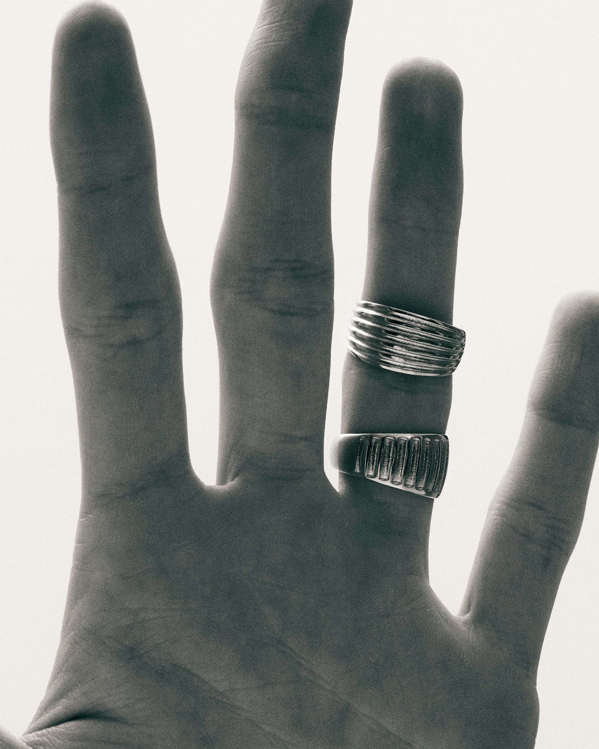 Black and white photo of hands wearing the Kion Ribbed Dome Rings by Enea Studio