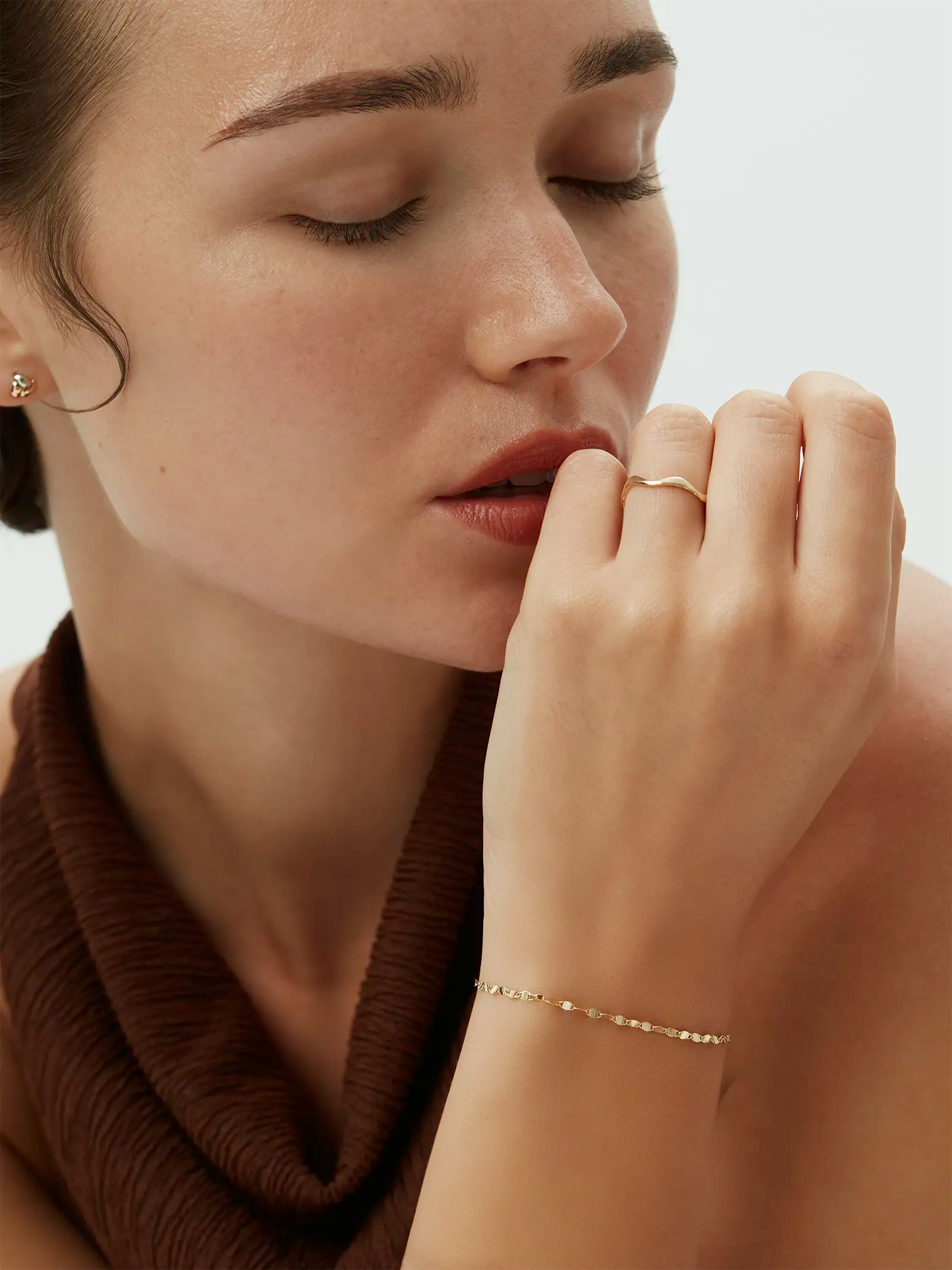 Model wearing the Kyma Organic Ring with a subtly wavy shape paired with a yellow gold bracelet. Enea Studio
