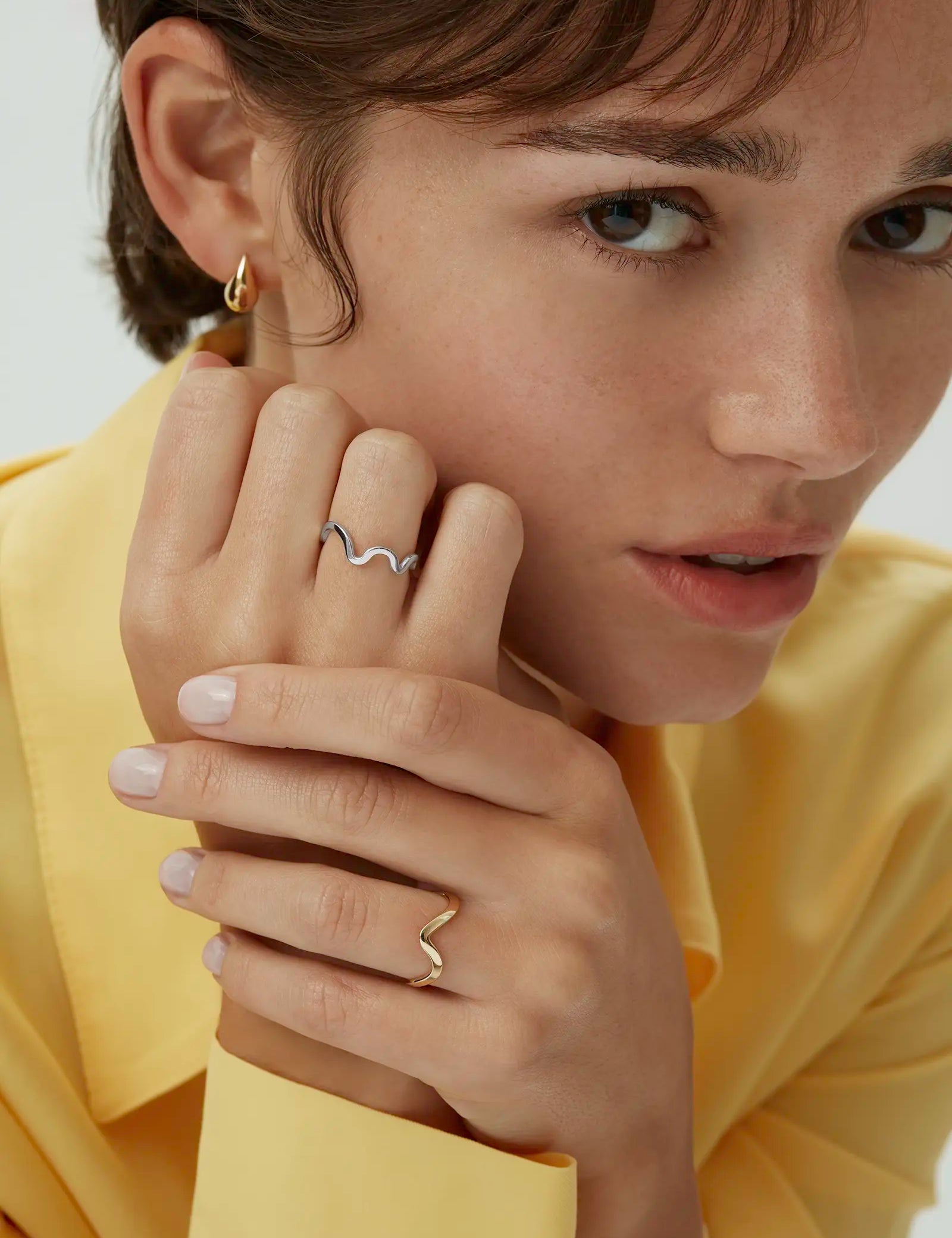Model wearing two wavy band rings including the 14k white gold Kyma Rhythm ring paired with the yellow gold version. Enea Studio